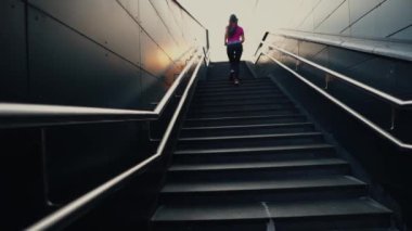 Güneş ışığına doğru koşan sportif bir bayanın çok geriden görünüşü
