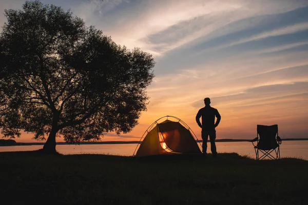 孤独な旅行者は湖畔の夕日を見る. — ストック写真