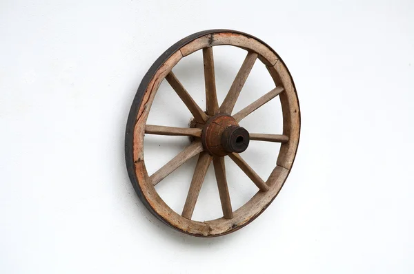 Старое колесо тележки на белой стене — стоковое фото