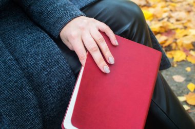 Bir sonbahar parkında bankta oturmuş günlük tutan bir kız. Güzel gri manikür..