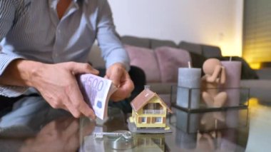 Yığınla parası ve ev modeli olan bir adam, emlak konsepti. 