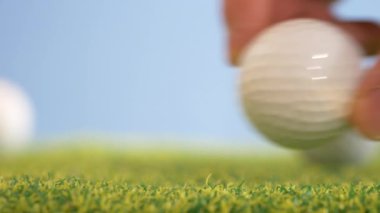 Golf topunu çimlerin üzerine koyan adamın kırpılmış görüntüleri.