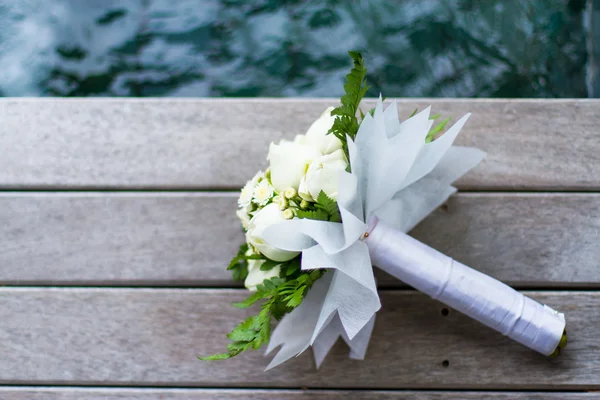 Anel de casamento no buquê de rosas brancas no chão de madeira — Fotografia de Stock