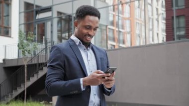 Afrika kökenli Amerikalı adam şehirde akıllı telefon yürüyüşlerinde iş uygulaması kullanıyor..