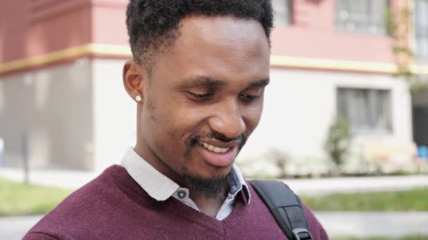 Portret van vrolijke Afro-Amerikaanse man met behulp van mobiele telefoon buiten. — Stockvideo