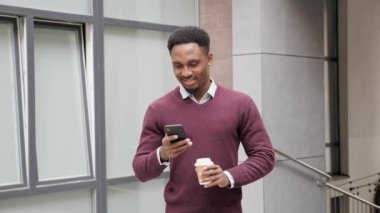 Afro-Amerikan Adam iş uygulamasını şehir merkezinde akıllı telefon yürüyüşlerinde kullanıyor..