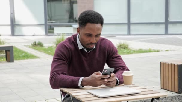 Pensive jonge zakenman freelancer het houden van smart phone controles e-mail buiten. — Stockvideo