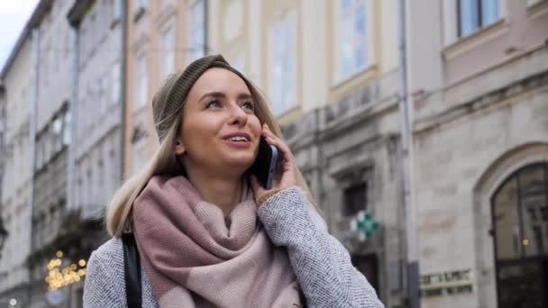 美丽的年轻女子,有着迷人的白发,可爱的秋衣在城市里.看到一位女商人在城市街道上讲着智能手机，真是令人惊叹. — 图库视频影像