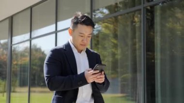 Asyalı işadamı akıllı telefonuna bakarken başarılı bir başlangıç yapıyor..