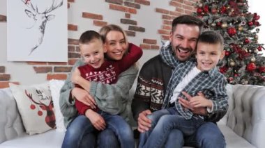 Genç bir aile Noel ağacının yanında birlikte vakit geçiriyorlar..