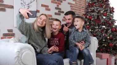 Genç mutlu aile akıllı telefon kayıtları kullanıyor. Noel tebrikleri..