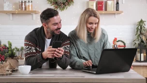 Pareja casada haciendo la compra de la venta de Navidad en línea en el teléfono inteligente y portátil. — Vídeos de Stock