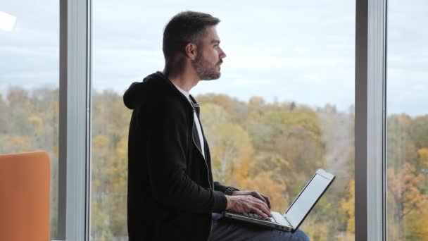 Magabiztos felnőtt üzletember gépelés laptop dolgozik az interneten, jóképű férfi professzionális felhasználó vállalkozó segítségével pc technológia csinál online munkát az irodában, gyönyörű kilátással az ablakból. — Stock videók