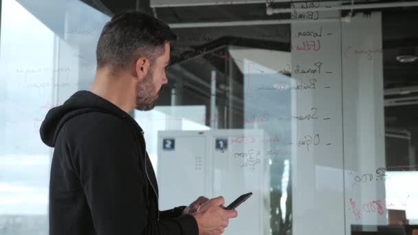 Professionell det programmerare affärsman som håller modern smarttelefon kontrollerar koden SMS tittar på glaset monter på kontoret. Ung manlig anställd med hjälp av modern mobil teknik affärsapp. — Stockvideo