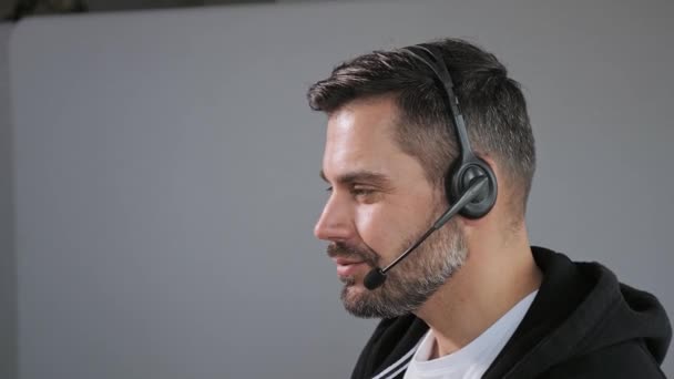 Bilgisayar Ekran ve veri sunucularıyla dolu Çağrı Merkezi Kontrol Odasında Bilgisayar üzerinde çalışırken Kulaklıkla Konuşan Yakışıklı Teknik Müşteri Desteği Uzmanının Portresini Kapat — Stok video