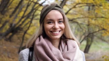 Güneşli bir günde, sonbaharda parkta yürüyen ve gülümseyen sarışın bir kadının portresi. Sonbaharda açık havada mutlu ve güzel bir kadının yüzü. Doğa özgürlüğü hissediyor. Doğal Güzellik Görünümü.