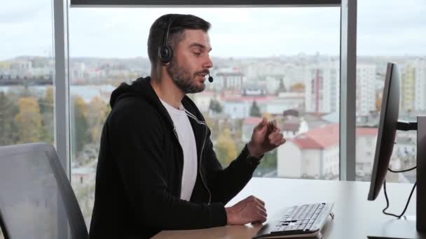 Lächelnder Geschäftsmann trägt ein drahtloses Headset, das Konferenzvideoanrufe auf seinem Laptop macht. Männlich professionell call center agent, hr manager having distance webcam chat job interview im büro stadt hintergrund. — Stockvideo