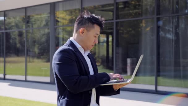 Coreano em terno formal usando laptop enquanto trabalhava distância. Conceito de negócio. — Vídeo de Stock