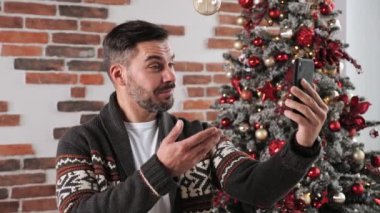 Gülümseyen adam Noel zamanı akıllı telefon kullanıyor..