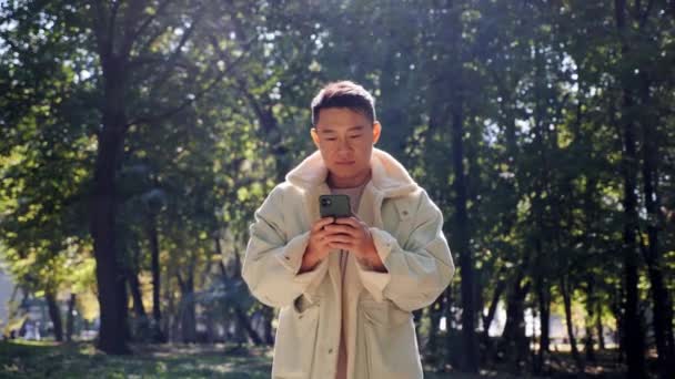 Kínai férfi sétál okostelefonnal. Guy chat a szociális hálózatok koncepció. — Stock videók