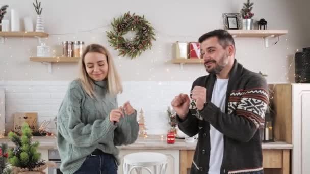 Ehepaar hat Spaß beim gemeinsamen Tanzen auf geschmückter heimeliger Weihnachtsküche. — Stockvideo