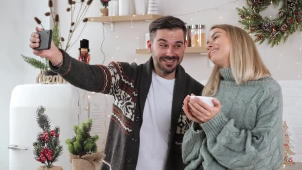 Feliz pareja de pie en casa cocina teniendo video llamada navidad saludos. — Vídeos de Stock