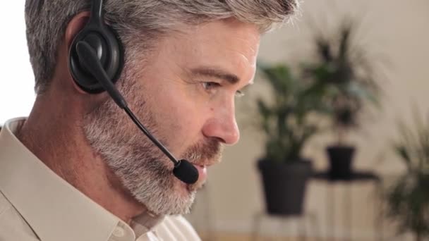 Adult kundsupport operatör assistent som arbetar på helpdesk med headset. — Stockvideo