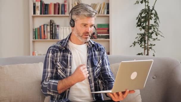 Biznesmen lub trener nosić słuchawki bezprzewodowe podejmowania wideokonferencji na laptopie. — Wideo stockowe