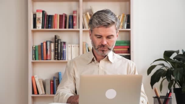 Συγκεντρωμένος πολυάσχολος άνθρωπος ελεύθερος επαγγελματίας χρησιμοποιώντας φορητό υπολογιστή και να κρατήσει σημειώσεις στο γραφείο στο σπίτι. — Αρχείο Βίντεο