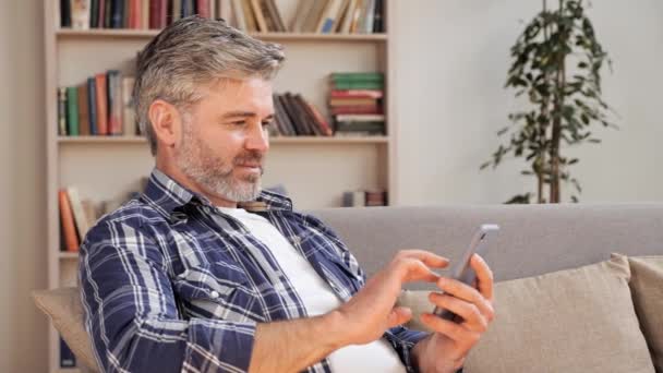男はオンラインコンテンツを楽しんで電話をスワイプします。現代の技術と人々の概念. — ストック動画