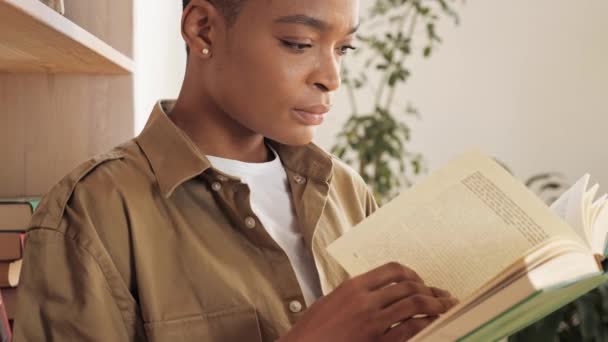 Attraktiv afrikansk kvinna läser bok hemma. Utbildning och stanna hemma koncept. — Stockvideo