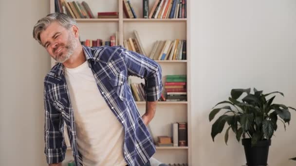 Homme d'affaires d'âge moyen debout à la maison ressentant douleur mal au dos expression fatiguée. — Video