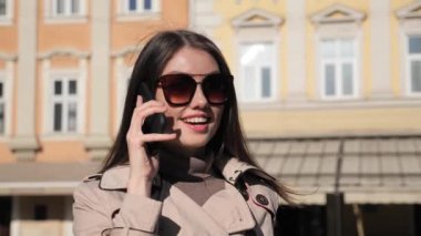 Şehir merkezinde dururken güzel bir iş kadını cep telefonuyla konuşuyor.. 