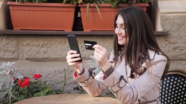 Aufgeregte Frau kauft online mit Kreditkarte und Smartphone ein. — Stockvideo