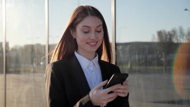 Pretty woman holing mobile phone standing near business center outdoors. — Stock Video