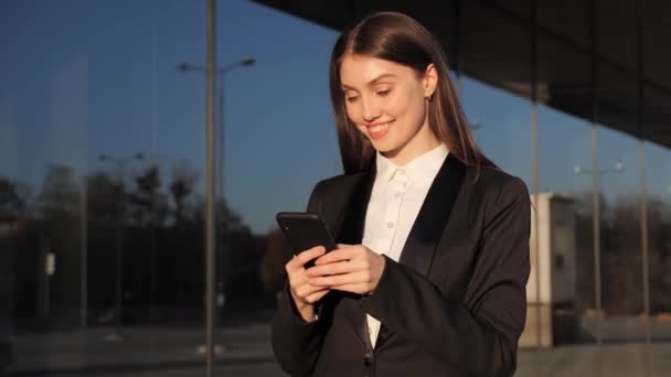 Donna d'affari sorridente Passeggiata vicino al centro ufficio Navigazione Smartphone moderno. — Video Stock