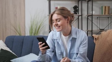 Mutlu eş e-ticarette alışveriş yapıyor kanepede oturuyor ve içeride gülüyor. Kredi kartı..