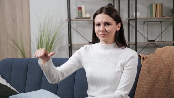 Portrait of girl with sign of dislike showing thumb down gesture at home. — Stock Video