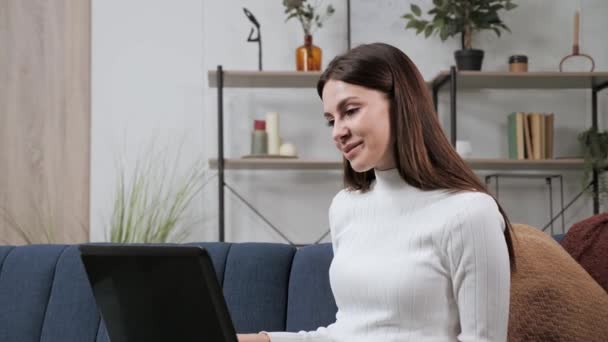 Jeune femme communique par chat vidéo en ligne, en utilisant un ordinateur portable à la maison. — Video