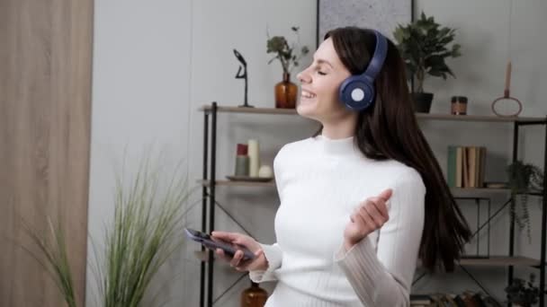 Jolie belle femme brune écoutant de la musique avec smartphone à la maison. — Video