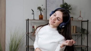 Evde eğlenen kız, kapalı alanda müzik dinlemek için yeni bir uygulama izliyor..