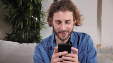 Rahat genç adam akıllı telefon kullanıyor haberleri kontrol ediyor, mobil oyunlar oynuyor..