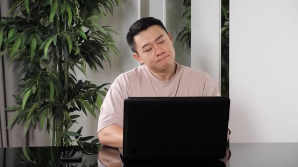 Asian man sit at home workplace experiences severe pain in neck overworking. — 图库视频影像