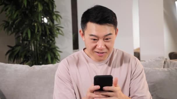 Asiatique gars regarder téléphone se sent excité reçu de bonnes nouvelles gagnant de loterie en ligne. — Video