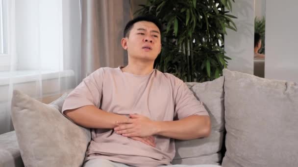Homem Asiático sentindo dor de estômago em casa, sintoma de gastrite, pancreatite. — Vídeo de Stock