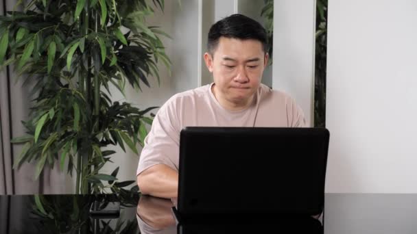 Close up view of handsome tired young asian man working on laptop. — 图库视频影像