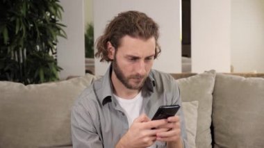 Şaşırdım genç adam kazanan akıllı telefonu tut iyi haberleri oku evde kazan.