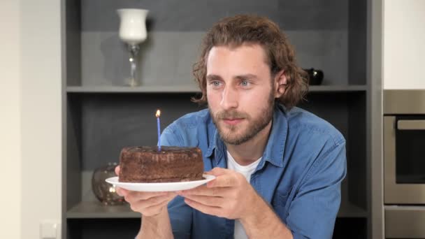 Jovem homem feliz celebrando aniversário sozinho bday com bolo de festa soprando vela. — Vídeo de Stock