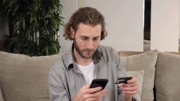 Attrayant homme caucasien barbu effectuant le paiement en ligne à la maison. Acheteur satisfait. — Video