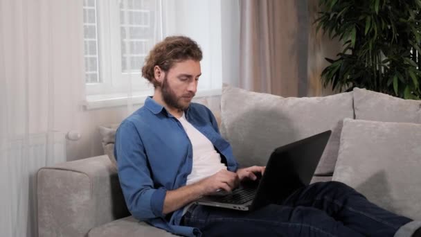 Przystojny dorosły, skupiony biznesmen relaksujący się pracując w domu za pomocą laptopa. — Wideo stockowe